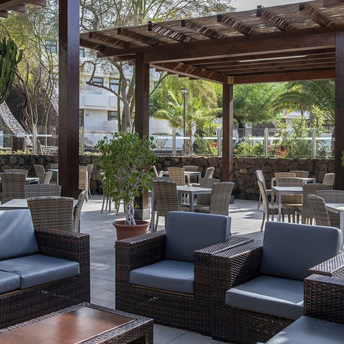 Gemütlicher Outdoor-Loungebereich und Restaurant unter Pergola im Impressive Zocos Lanzarote.