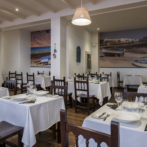 Geräumiges, helles Restaurant im Impressive Zocos Lanzarote mit maritimen Wandbildern und rustikalen Holzstühlen.