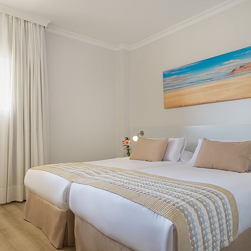 Habitación doble luminosa y moderna en Impressive Zocos Lanzarote con cama grande, mesas de noche y ventana.