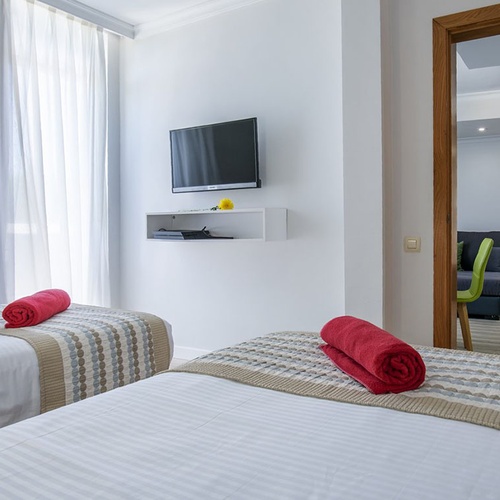 Helles Zweibettzimmer im Impressive Zocos Lanzarote, modern eingerichtet mit TV und separatem Wohnbereich.