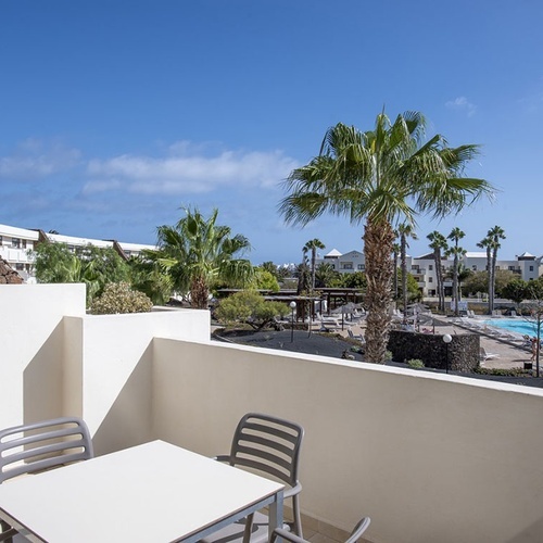 Blick vom Balkon auf die Hotelanlage des Impressive Zocos Lanzarote mit Pool und Palmen.