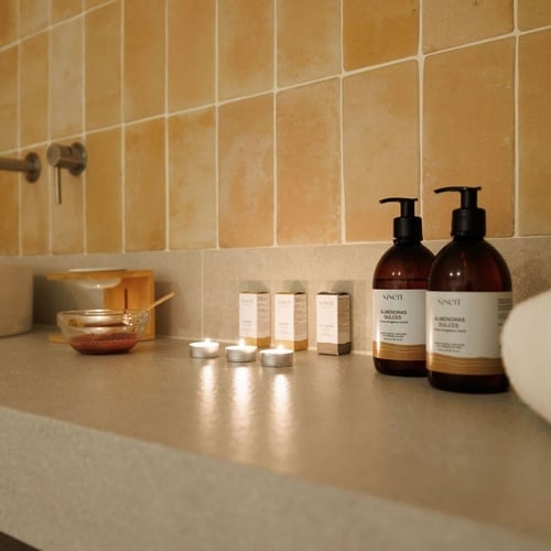 un comptoir de salle de bain avec des bouteilles de santé et des bougies allumées