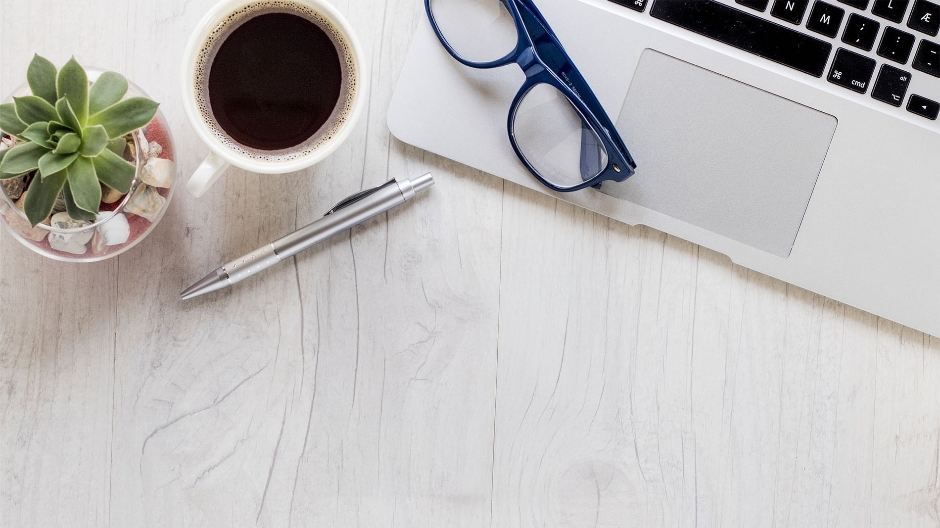 une tasse de café , un stylo , des lunettes et un ordinateur portable sur une table