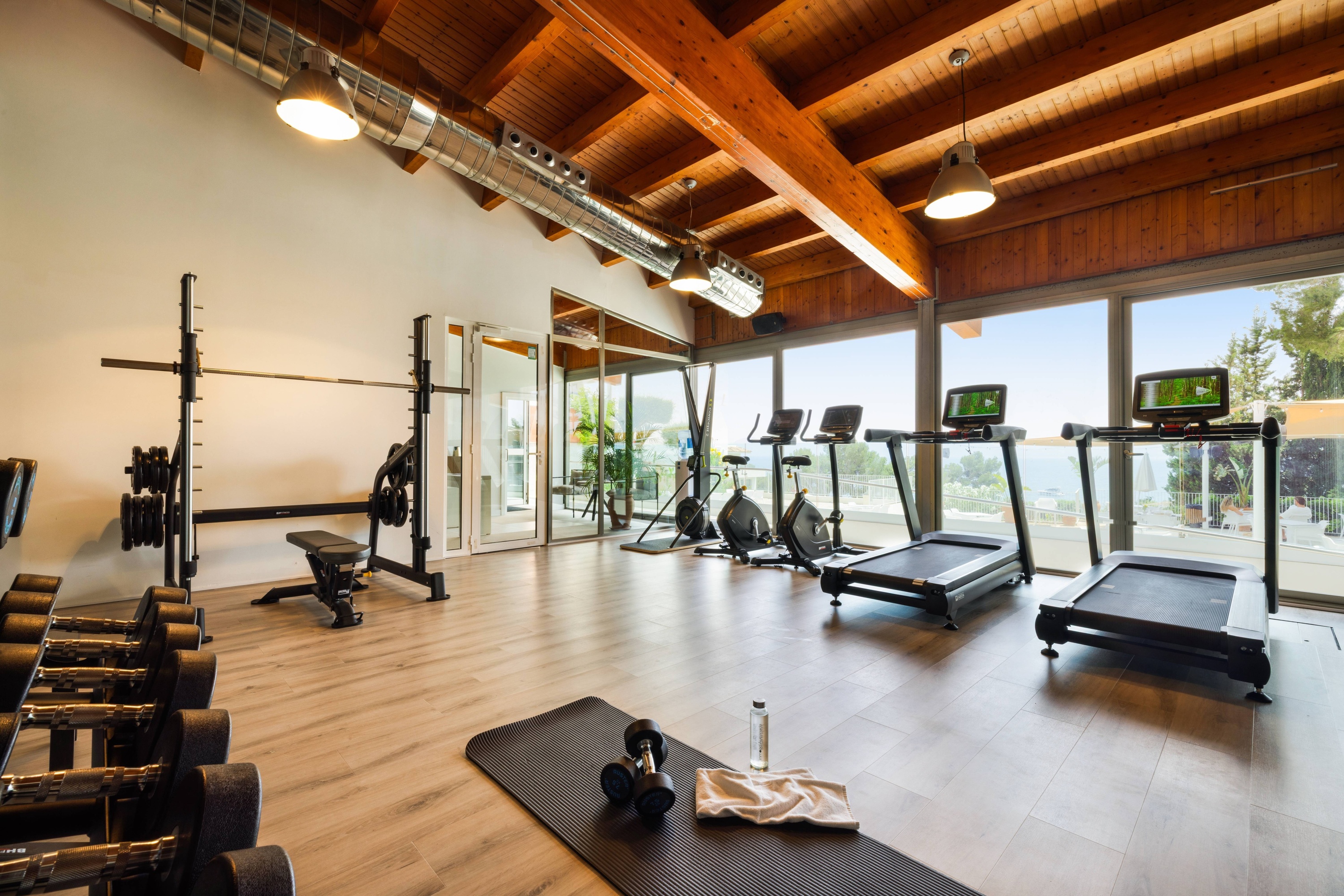 a gym with treadmills dumbbells and a large window