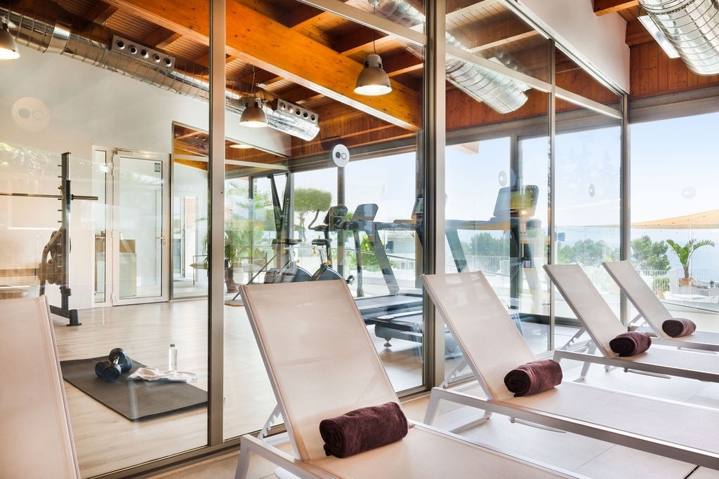 une salle de sport avec un tapis roulant et des chaises longues
