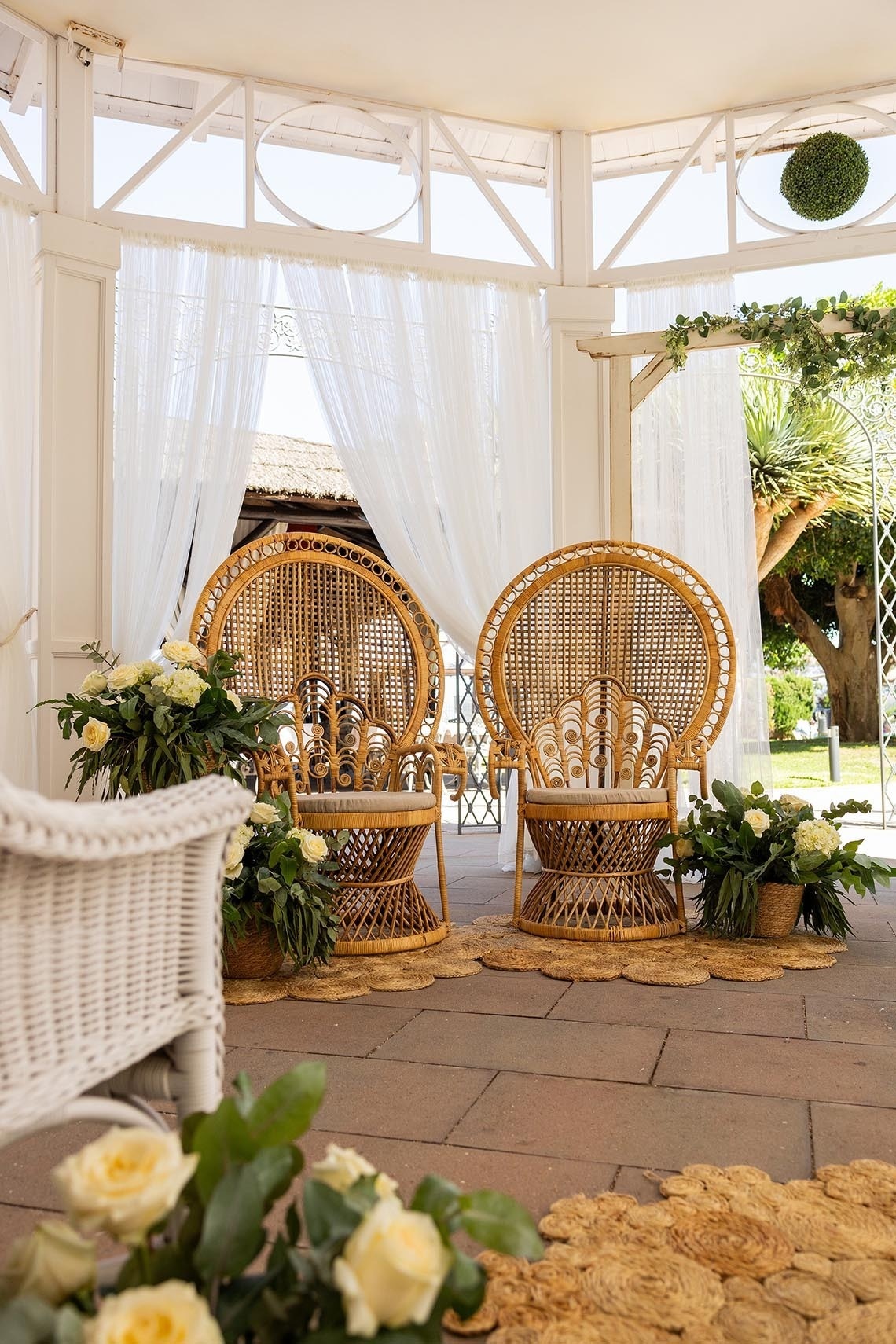 dos sillas de mimbre y una silla blanca en un patio