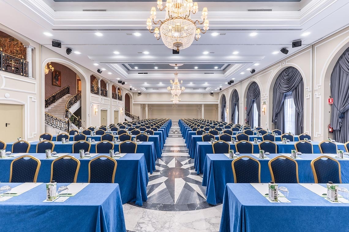 una sala de conferencias llena de mesas y sillas azules
