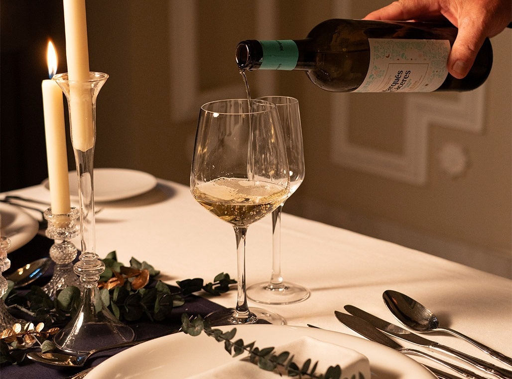 una mujer sostiene un vaso de vino junto a un plato de comida