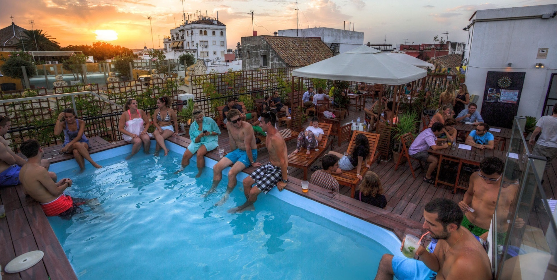 un grupo de personas se sienta alrededor de una piscina al atardecer