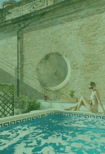 a woman sits on the edge of a swimming pool