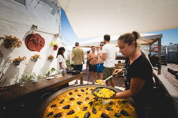 a woman in a black shirt is preparing a paella