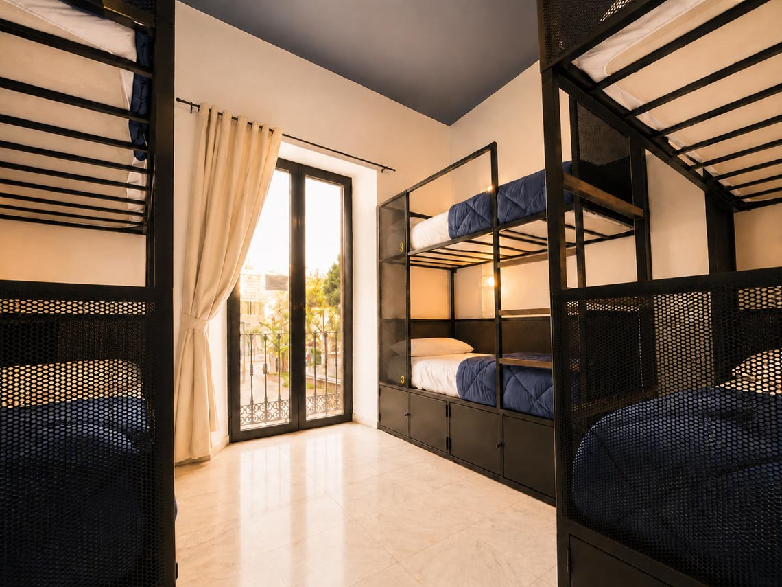 Modern hostel dorm room with bunk beds, storage, and balcony view. JOY: Corporativa