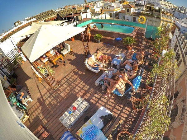 a group of people are gathered around a pool on a rooftop