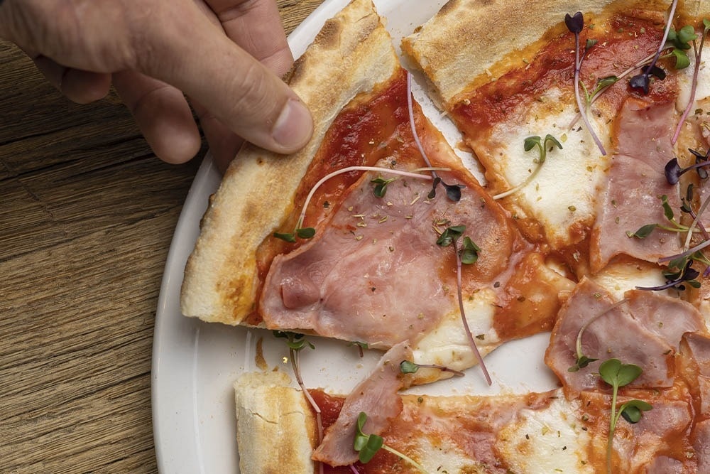 una pizza está sobre una tabla de cortar de madera