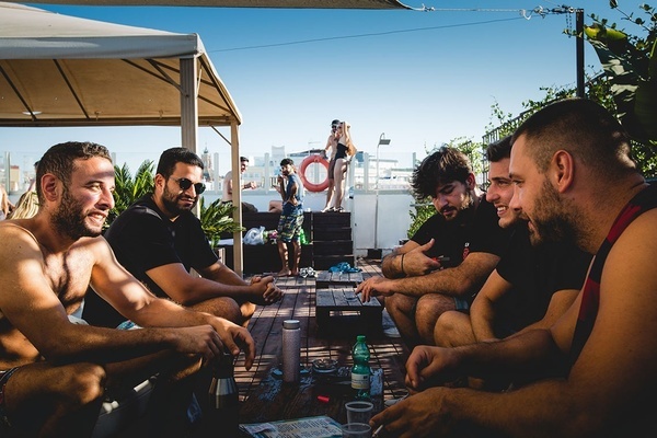 a group of people are gathered around a pool on a rooftop