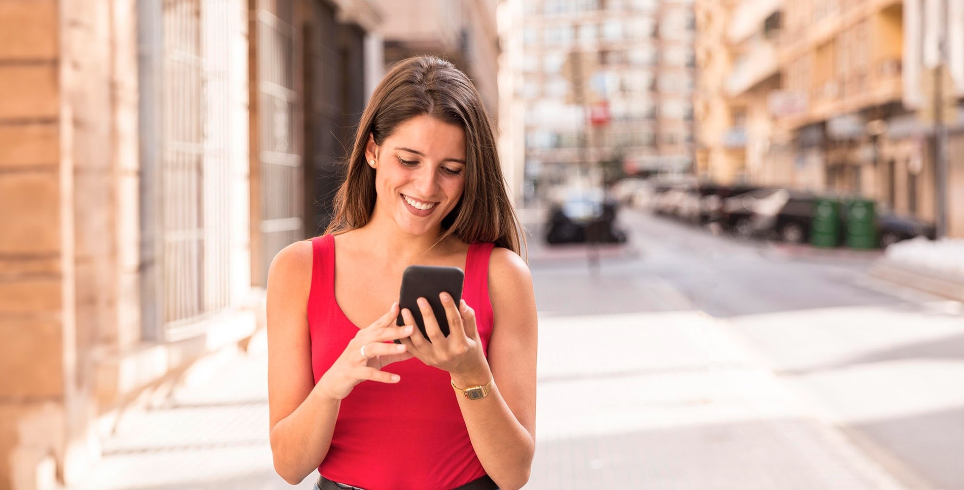 una mujer sonríe mientras usa su teléfono celular