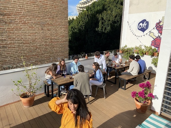 un grupo de personas se relajan en un patio con una piscina en el fondo