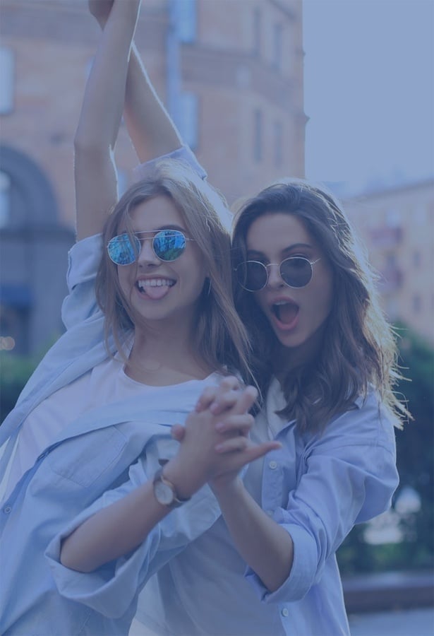 dos chicas con gafas de sol y camisa azul están bailando