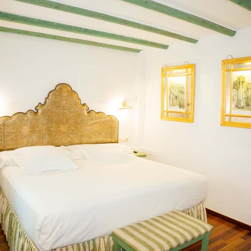 Luxurious bedroom with ornate headboard and art, ideal for your Juderia: Cordoba stay.