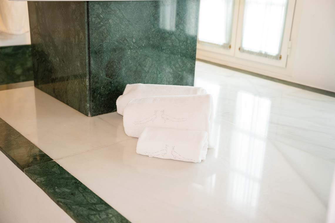 Luxurious white towels with peacock embroidery on marble floor at Juderia: Cordoba hotel.