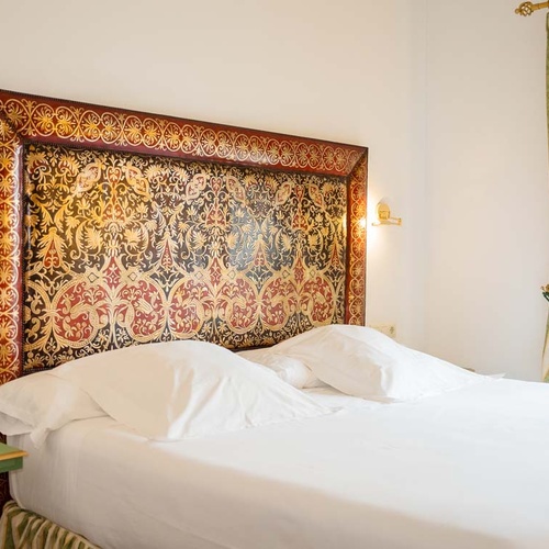Luxurious headboard in a Juderia: Cordoba hotel room, with elegant bedding and curtains.