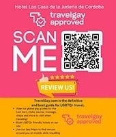Este póster promociona el Hotel Las Casa de la Juderia de Cordoba como un establecimiento aprobado por TravelGay y anima a los usuarios a escanear un código QR para revisar el hotel y explorar TravelGay.com, una guía para viajes LGBTQ+.