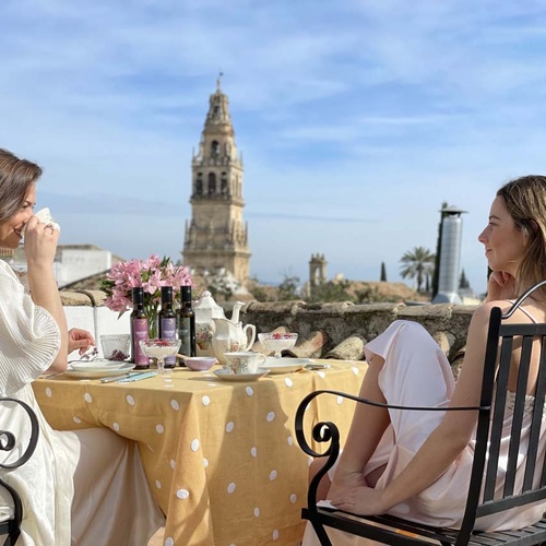 Two women enjoy tea on a rooftop terrace with views of La Juderia: Cordoba's historic district.