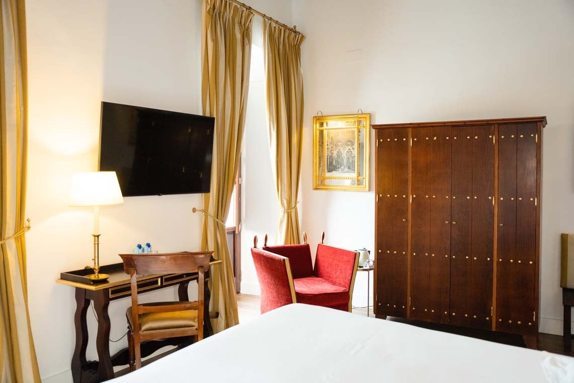 Elegant hotel room in Juderia: Cordoba with TV, desk, armchair, and wardrobe.