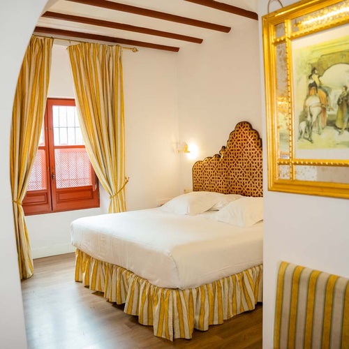 Elegant bedroom in Juderia: Cordoba with a queen bed, yellow curtains, and art.