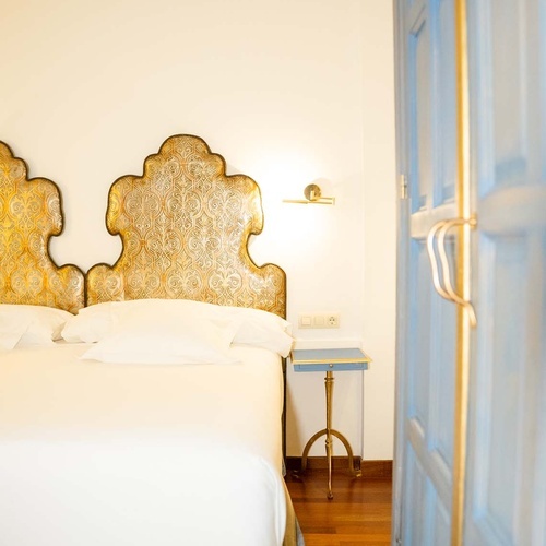 Luxurious Juderia, Cordoba hotel room with ornate headboards and blue door.