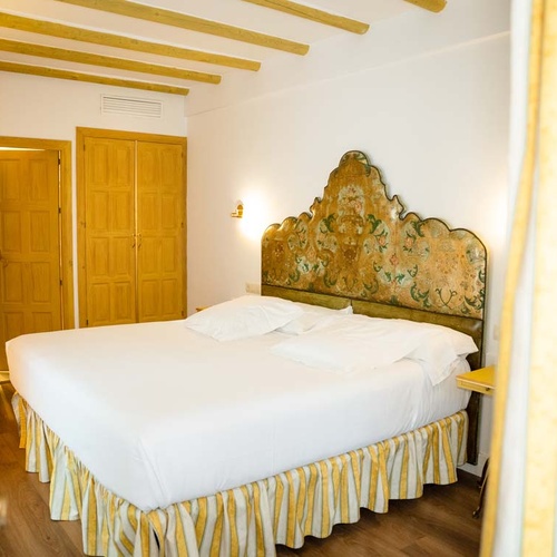 Elegant bedroom with a unique headboard and wooden doors, perfect for a stay in Juderia: Cordoba.