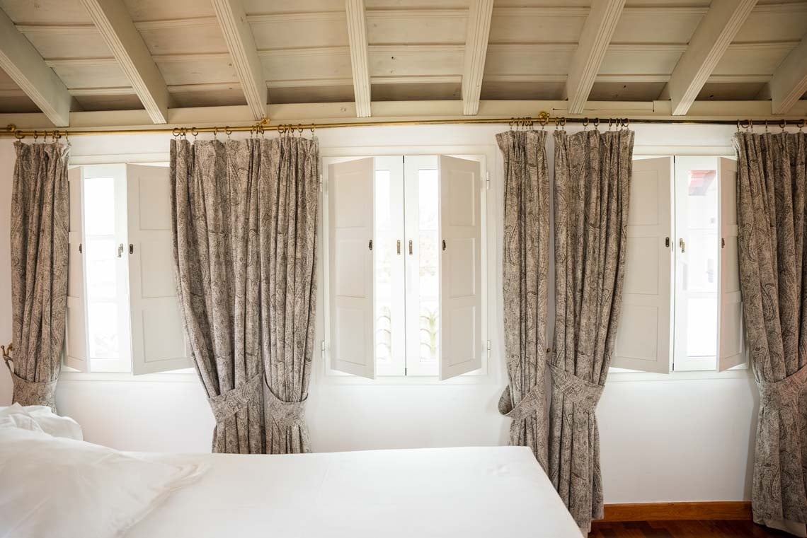 Classic shutters and paisley curtains frame windows in a Juderia: Cordoba hotel room.