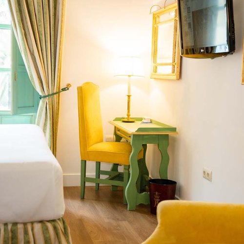 Charming Juderia: Cordoba hotel room with yellow chair, desk, and comfortable bed.