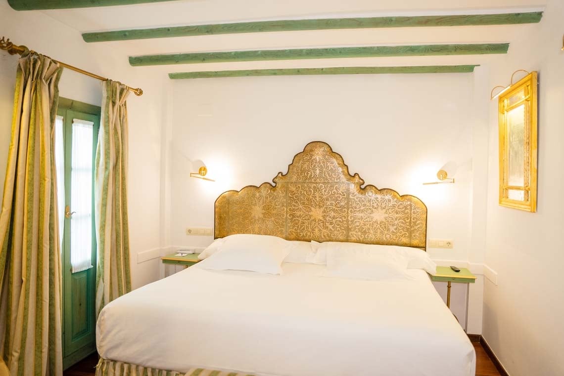 Elegant bedroom with ornate headboard in Juderia: Cordoba hotel.