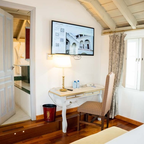 Luxury hotel room in Juderia: Cordoba, featuring a desk, TV, and open doorway to a bathroom.