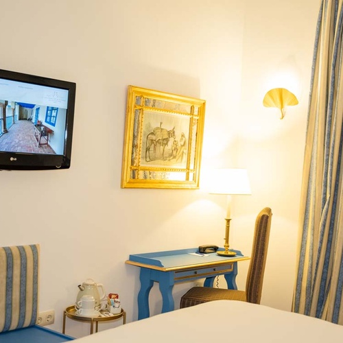 Elegant hotel room in Juderia: Cordoba with desk, TV, and striped curtains.