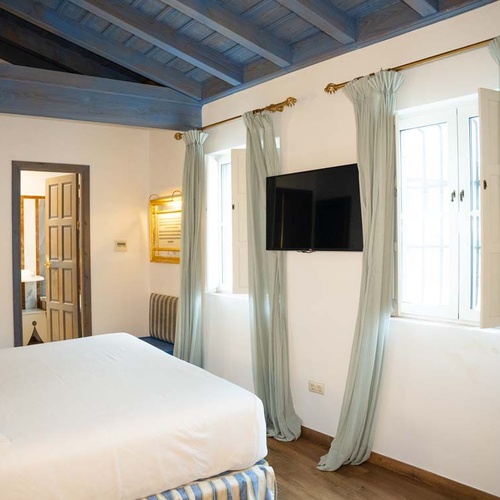 Charming Juderia: Cordoba hotel room with blue beams, twin beds, and a TV.