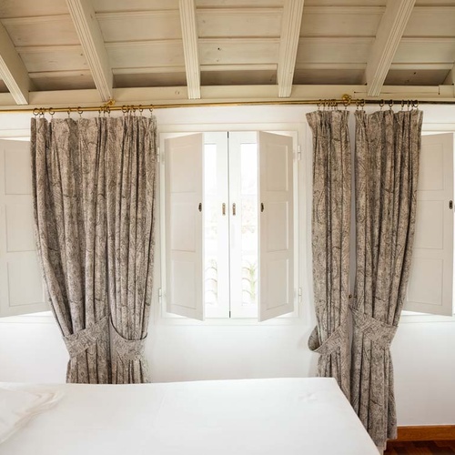 Elegant curtains frame open shutters in a Juderia: Cordoba hotel room, overlooking natural light.