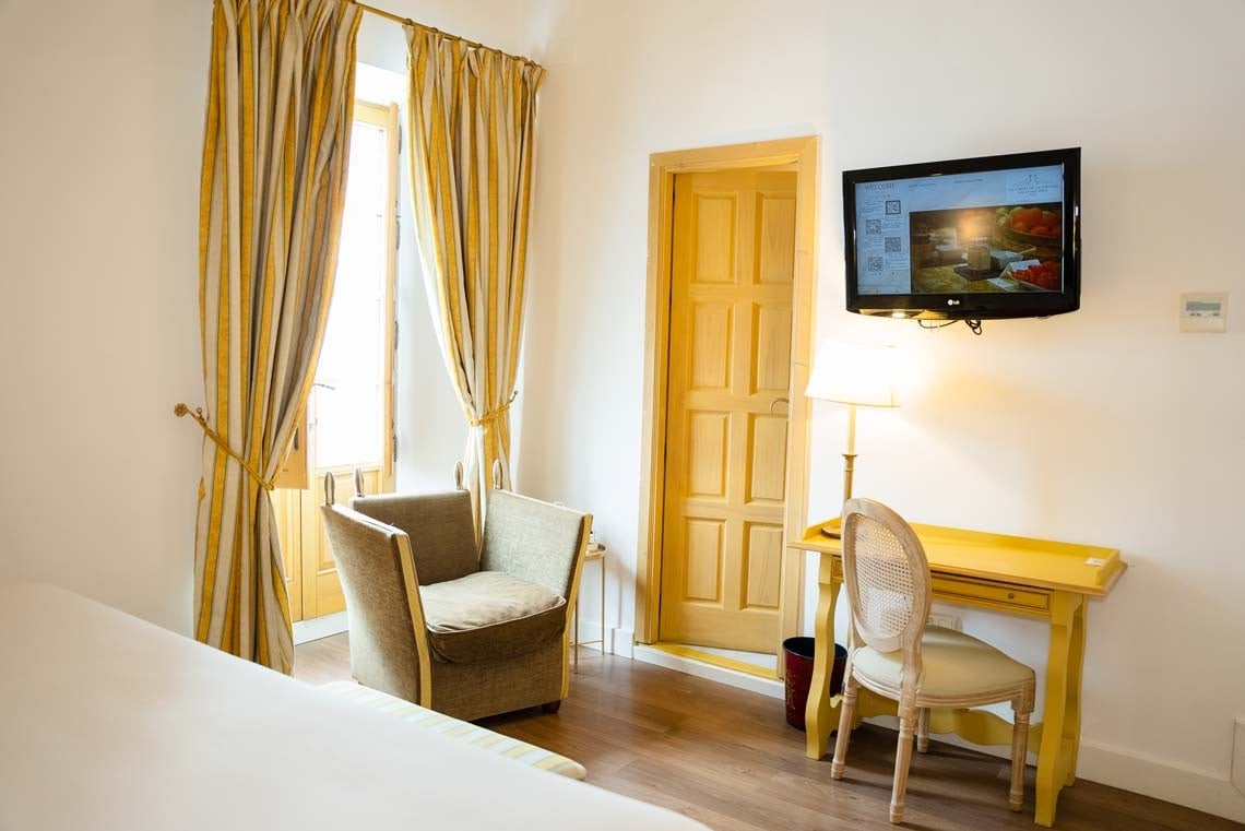 Elegant hotel room with a desk, chair, TV, and striped curtains in Juderia: Cordoba.