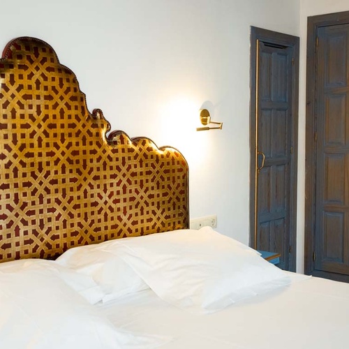 Luxurious Judería: Córdoba hotel room with ornate headboard and rustic doors.