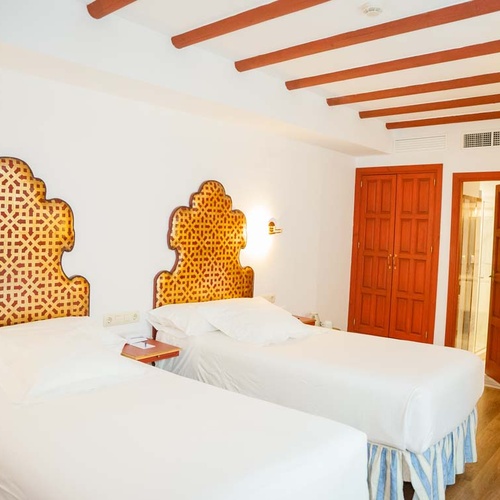 Cozy twin beds with decorative headboards in a Juderia: Cordoba hotel room.