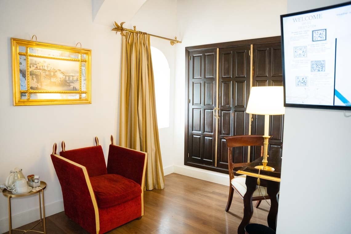 Elegant hotel room in Juderia: Cordoba with red armchair and painting.