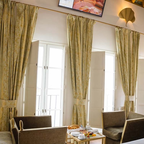 Elegant hotel room with patterned curtains near Juderia: Cordoba views.