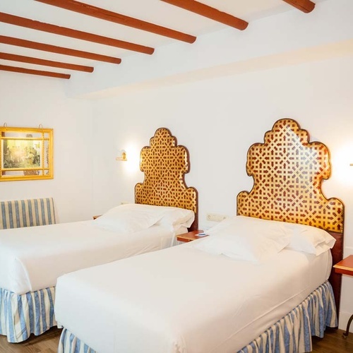 Cozy twin room in Juderia: Cordoba, featuring ornate headboards, plush beds, and traditional decor.