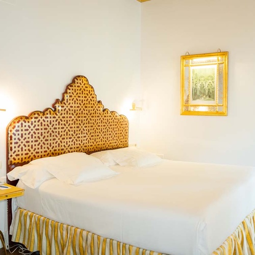 Luxurious Juderia: Cordoba hotel room with ornate headboard and gold accents.
