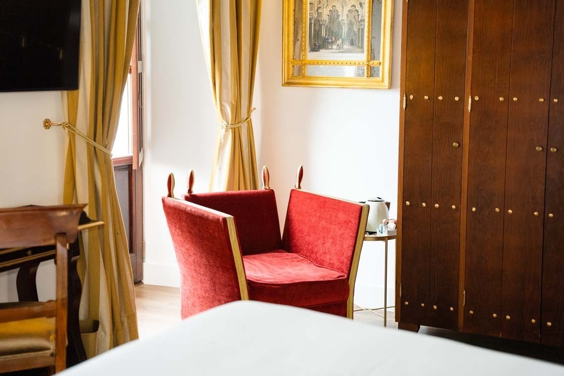 Luxurious red velvet armchair in a Juderia: Cordoba hotel room.