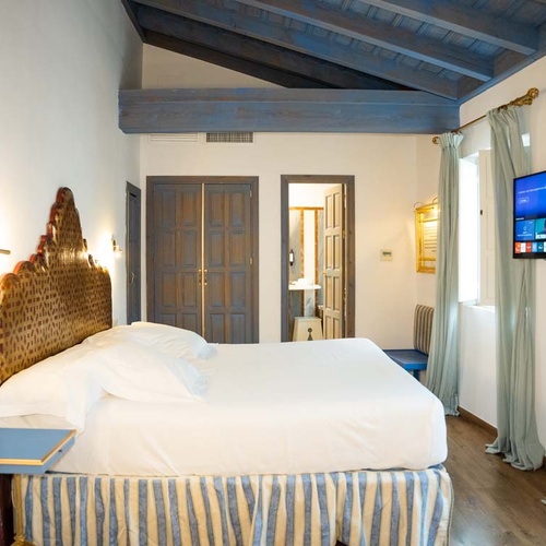 Elegant bedroom in Juderia: Cordoba featuring a king-size bed, vintage headboard, and modern TV.