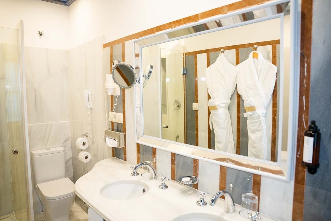 Luxurious bathroom with robes, double sinks, and toiletries at Judería: Cordoba hotel.