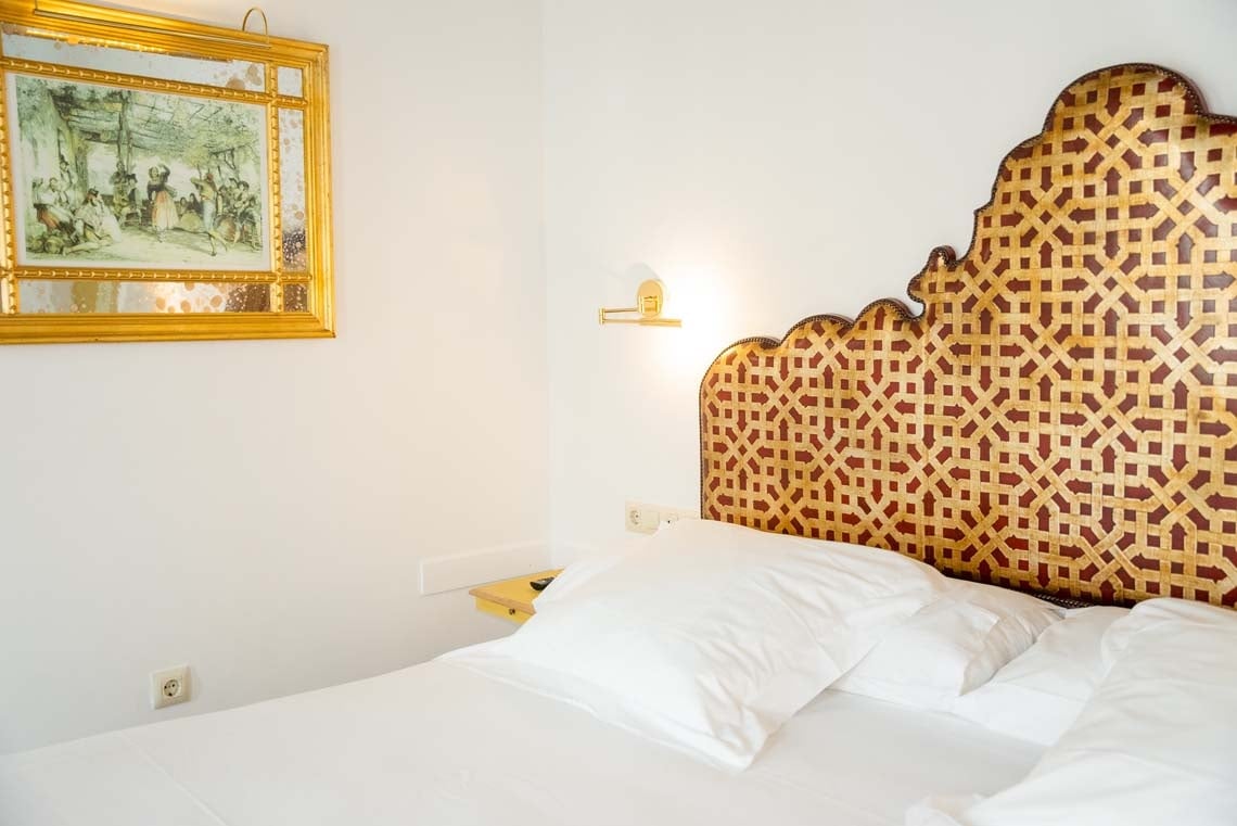 Elegant bedroom with ornate headboard, a nod to Juderia: Cordoba's rich history.