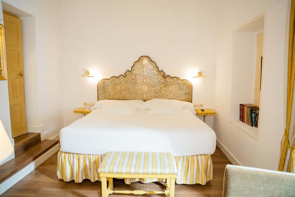 Luxurious Juderia: Cordoba hotel room with ornate headboard and comfortable bed.